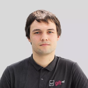Portretinė nuotrauka – jaunas vyras trumpais tamsiais plaukais, vilkintis juodą polo marškinėlius su „KTU gifted“ logotipu, žvelgia tiesiai į kamerą šviesiame fone.