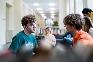 Du vaikinai neformaliai bendraujantys universiteto poilsio erdvėse.