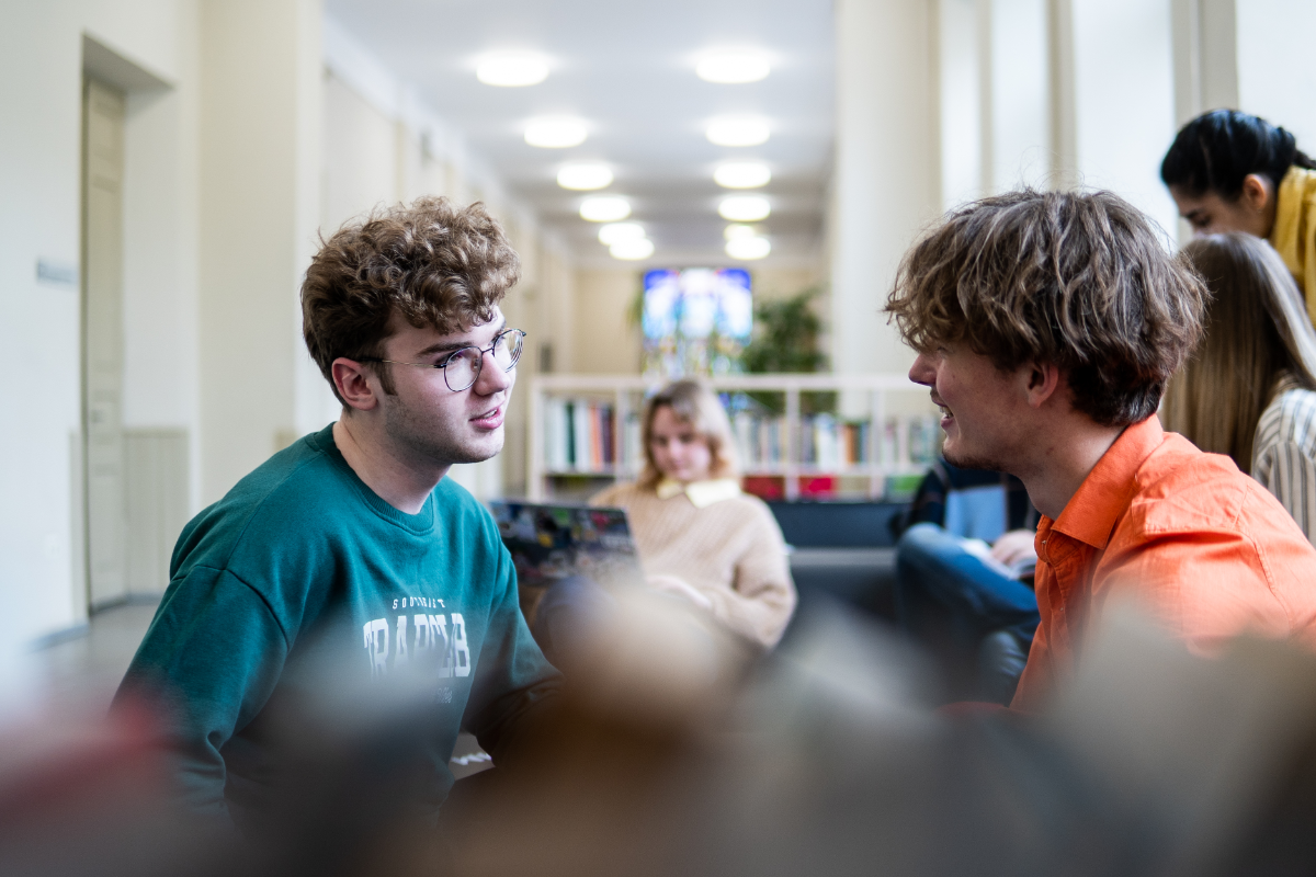 Du vaikinai neformaliai bendraujantys universiteto poilsio erdvėse.